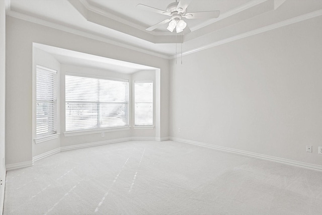 carpeted empty room with a tray ceiling, ceiling fan, and ornamental molding