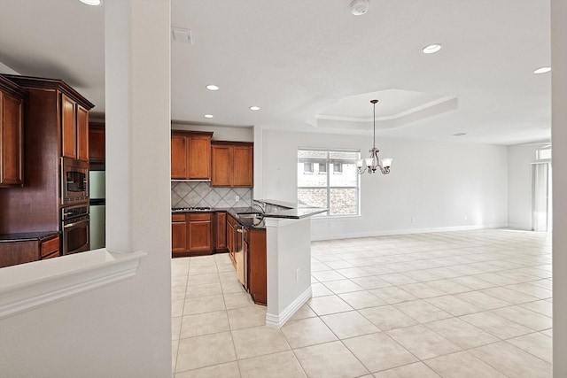 kitchen with a raised ceiling, a notable chandelier, decorative backsplash, light tile patterned floors, and appliances with stainless steel finishes