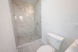 bathroom with tiled shower and toilet