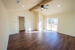 spare room with lofted ceiling with beams, dark hardwood / wood-style floors, and ceiling fan