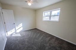 unfurnished room with ceiling fan and dark carpet