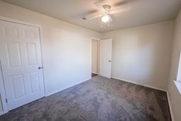 unfurnished bedroom featuring a closet, dark carpet, and ceiling fan