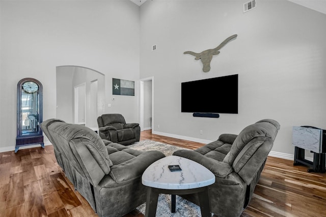 living room with hardwood / wood-style floors and a towering ceiling