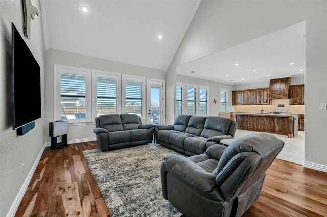 living room with light hardwood / wood-style floors, high vaulted ceiling, and sink