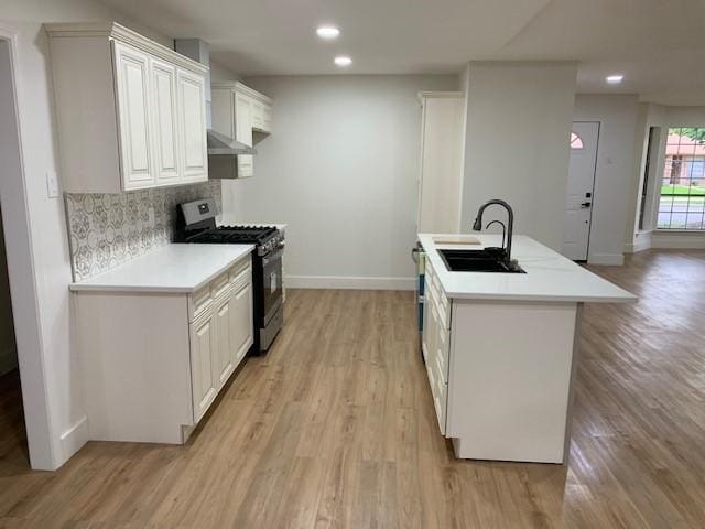 kitchen featuring white cabinetry, sink, stainless steel gas range, extractor fan, and decorative backsplash