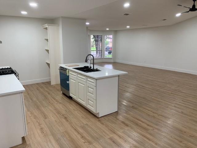 kitchen featuring stainless steel dishwasher, sink, light hardwood / wood-style flooring, white cabinetry, and an island with sink