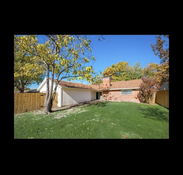 rear view of property featuring a lawn