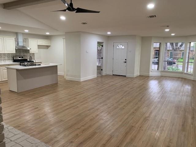 interior space featuring vaulted ceiling with beams, ceiling fan, and light hardwood / wood-style flooring