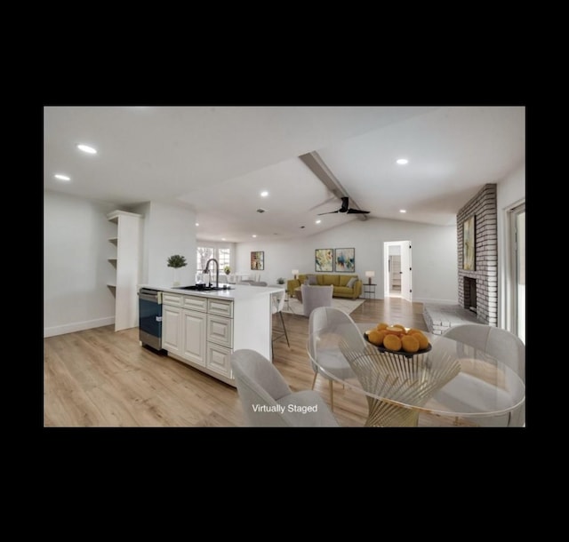 kitchen with a kitchen island with sink, sink, light hardwood / wood-style flooring, ceiling fan, and white cabinetry