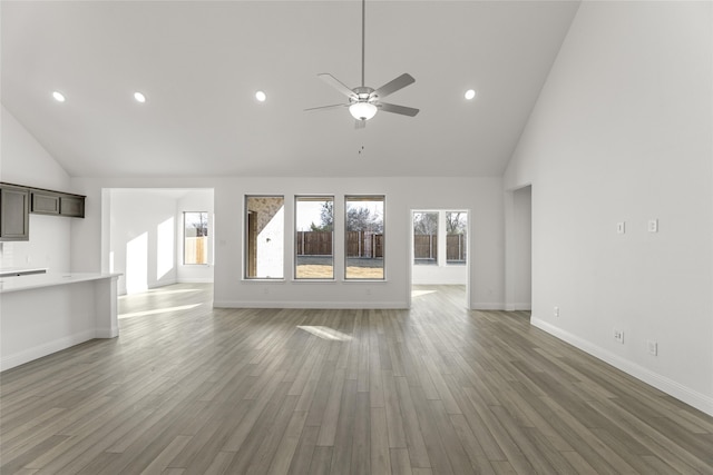 unfurnished living room with wood-type flooring, high vaulted ceiling, and ceiling fan