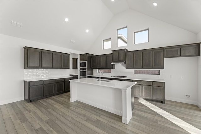 kitchen with sink, dark brown cabinets, an island with sink, and appliances with stainless steel finishes