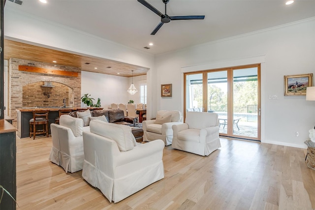 living room with ceiling fan, crown molding, and light wood-type flooring