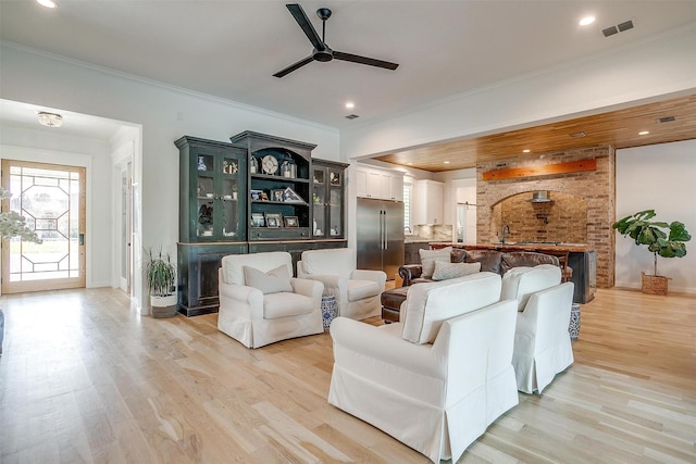 living room featuring ceiling fan, sink, light wood-type flooring, and ornamental molding