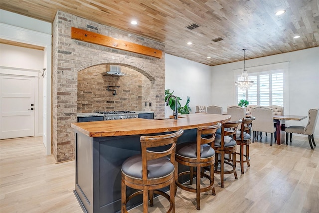 interior space with sink, wood counters, light hardwood / wood-style flooring, decorative light fixtures, and wood ceiling