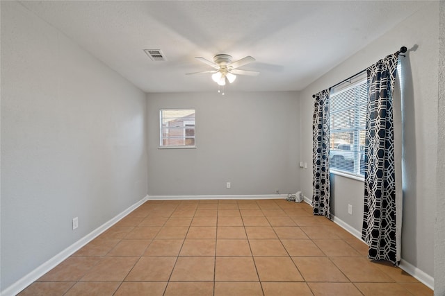 spare room featuring ceiling fan, light tile patterned floors, and a textured ceiling