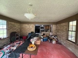 unfurnished living room featuring carpet, brick wall, and a textured ceiling