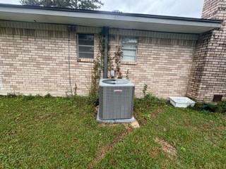 view of property exterior with central air condition unit and a lawn