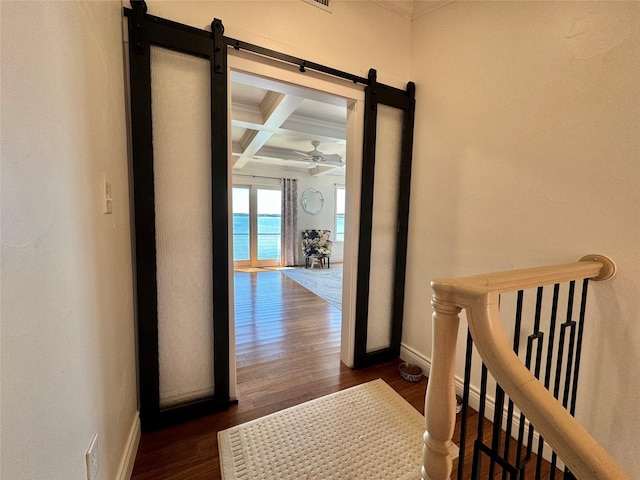 hallway featuring dark wood-type flooring, coffered ceiling, beamed ceiling, a water view, and ornamental molding