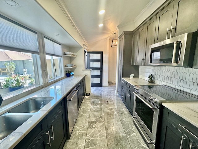 kitchen featuring sink, stainless steel appliances, light stone counters, decorative light fixtures, and decorative backsplash