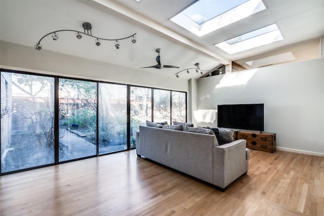 living room with ceiling fan, lofted ceiling with skylight, and light wood-type flooring