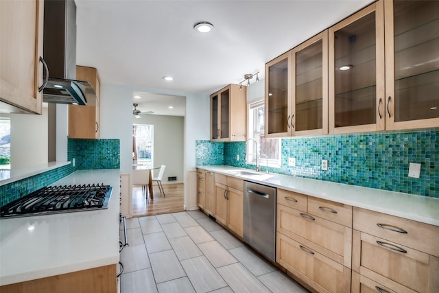 kitchen with sink, ceiling fan, stainless steel appliances, light brown cabinets, and wall chimney exhaust hood