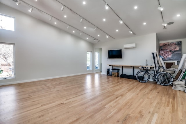 living room featuring a wall mounted air conditioner, light hardwood / wood-style flooring, and a high ceiling