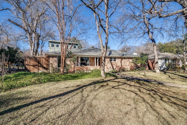 view of front of home with a front yard, brick siding, and fence