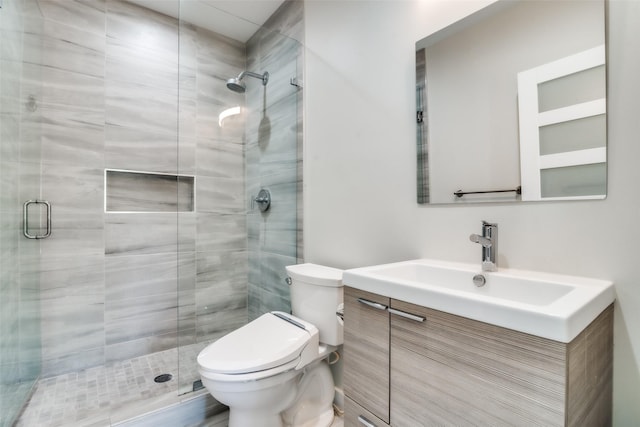 bathroom featuring vanity, a shower with door, and toilet