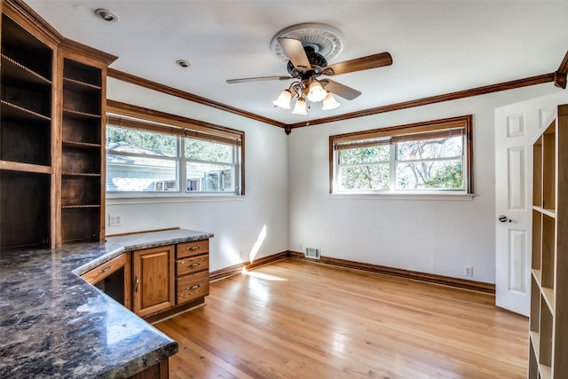 unfurnished office featuring a healthy amount of sunlight, light hardwood / wood-style flooring, ornamental molding, and ceiling fan