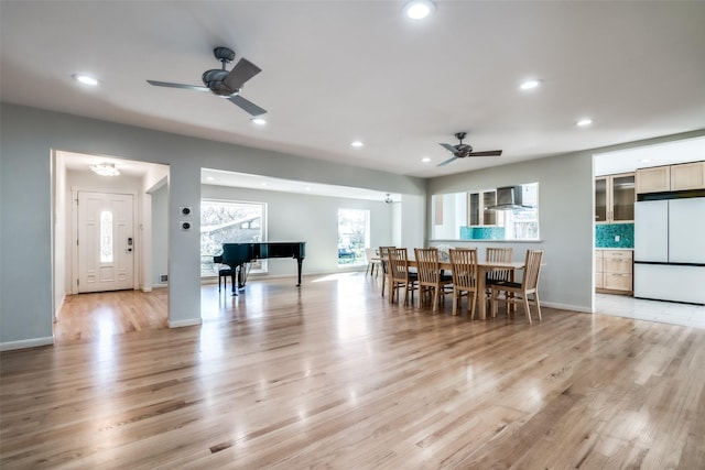 dining space with ceiling fan and light hardwood / wood-style flooring