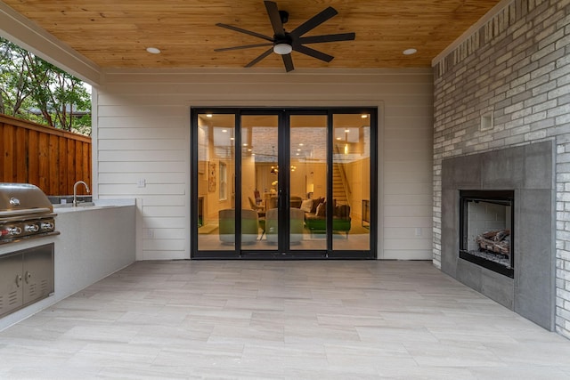 view of patio / terrace with an outdoor kitchen, ceiling fan, sink, grilling area, and an outdoor fireplace