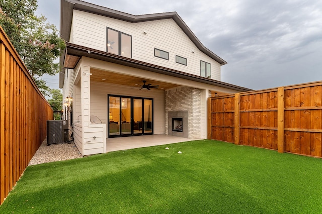 back of property featuring central AC, a patio area, a yard, and a brick fireplace