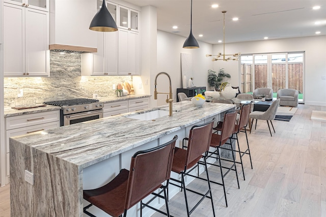 kitchen with white cabinets, custom exhaust hood, sink, and stainless steel stove