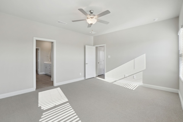 unfurnished bedroom featuring light carpet, ceiling fan, and ensuite bath