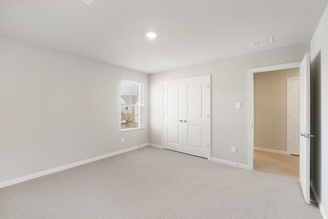 unfurnished bedroom featuring light carpet and a closet