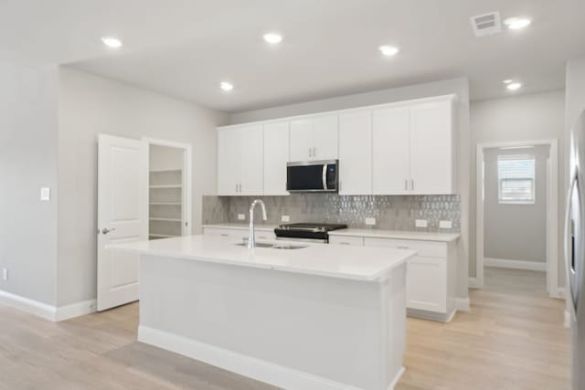 kitchen featuring white cabinets, appliances with stainless steel finishes, sink, and a center island with sink