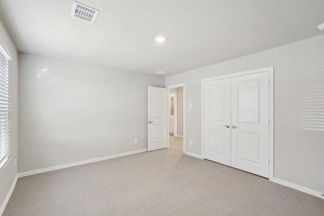 unfurnished bedroom with a closet and light carpet