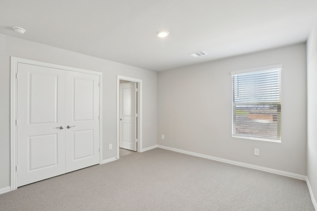 unfurnished bedroom with light carpet and a closet