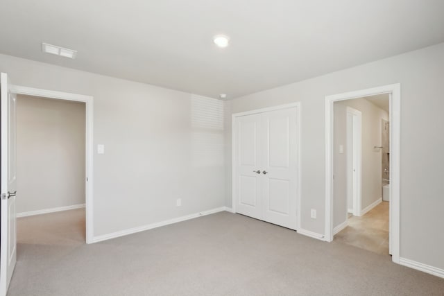 unfurnished bedroom featuring light carpet and a closet