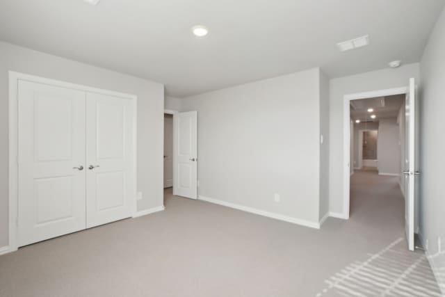 unfurnished bedroom with light colored carpet and a closet