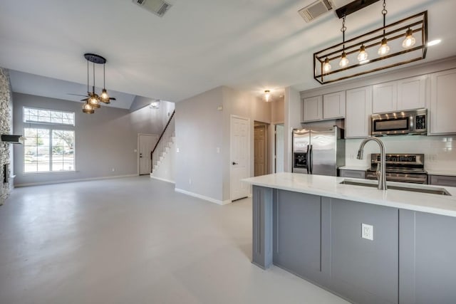 kitchen with gray cabinets, sink, hanging light fixtures, and appliances with stainless steel finishes