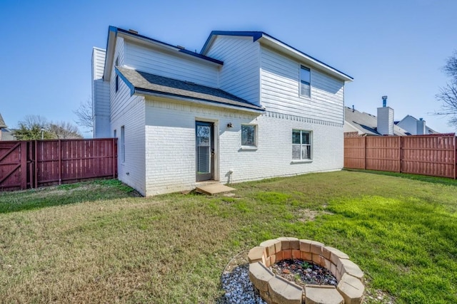 back of property with a yard and a fire pit