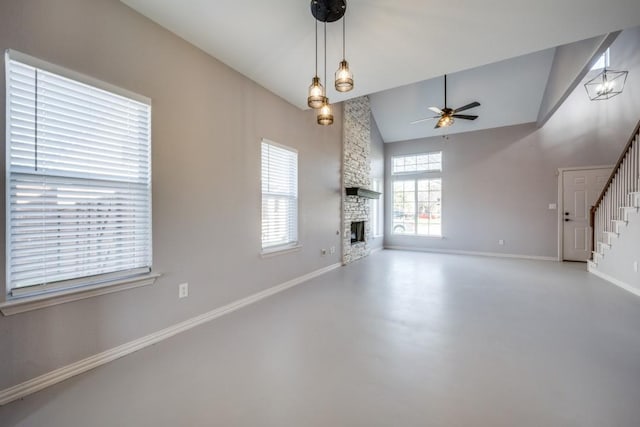 unfurnished living room with ceiling fan with notable chandelier, concrete flooring, a fireplace, and high vaulted ceiling