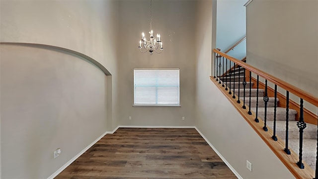 interior space with wood-type flooring, a high ceiling, and an inviting chandelier