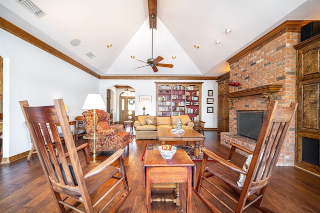 living room featuring ceiling fan, ornamental molding, dark hardwood / wood-style flooring, a brick fireplace, and beamed ceiling