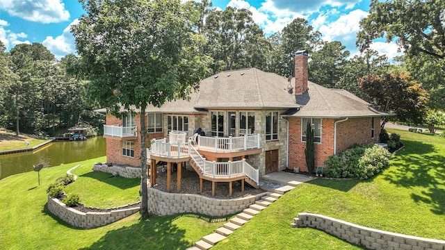 back of property with a deck with water view and a yard