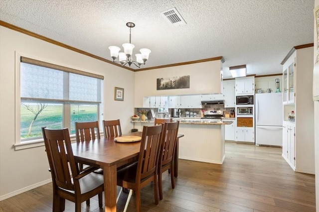 dining room with hardwood / wood-style floors, a textured ceiling, an inviting chandelier, and crown molding