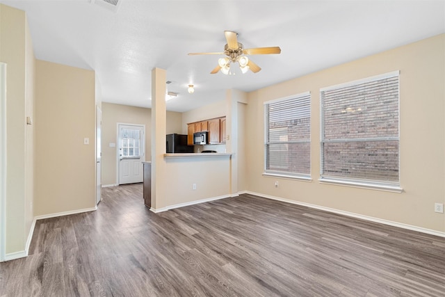 unfurnished living room with ceiling fan, dark wood-type flooring, and a healthy amount of sunlight