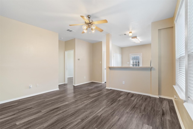 unfurnished room with dark wood-style floors, ceiling fan, visible vents, and baseboards