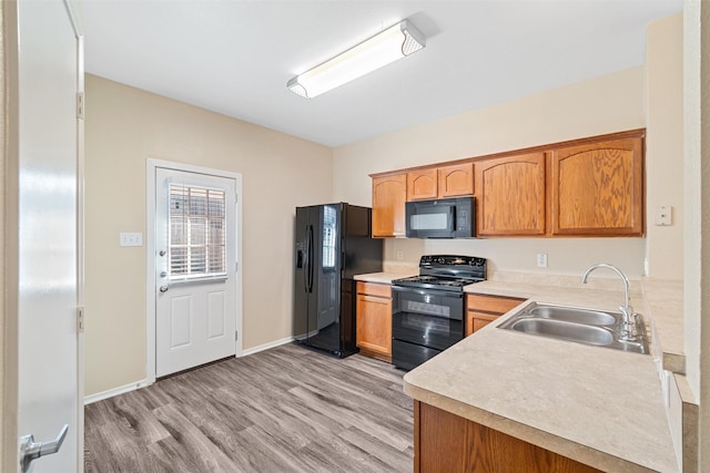 kitchen featuring sink, black appliances, and light hardwood / wood-style floors